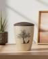 Preview: Special pet urn for dogs in beige with a velvety surface and brown lid, adorned with a pad printed motif of a branched tree and a loyal sitting dog silhouette – A dignified keepsake for the home.